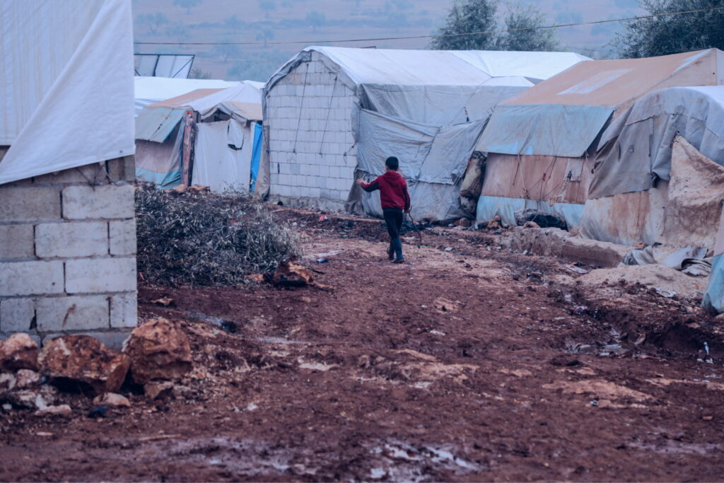 A boy walks through a displacement camp in NW Syria. Credit: A. Hammam/INSO