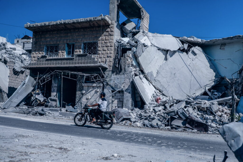 A man drives through a destroyed neighbourhood in NW Syria. Credit: A. Hammam/INSO
