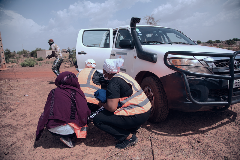 HEIST participants in Mali take cover behind a car door during a fake checkpoint scenario