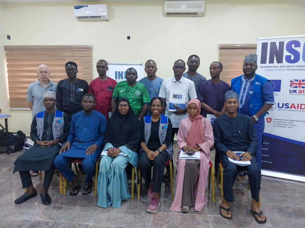 Group of training participants standing and sitting in front of INSO roll-up banner.